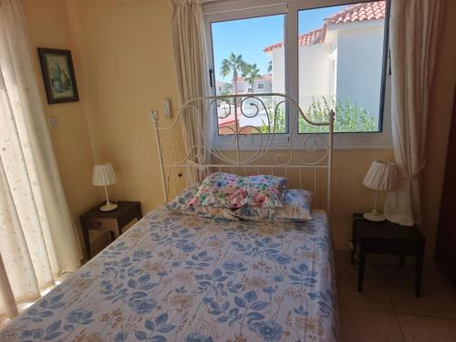 1 dormitorio con 1 cama con ventana y colcha en Carolyn Villa is a Luxury 4-Bedroom Villa with Private Pool in Ayia Napa, en Ayia Napa
