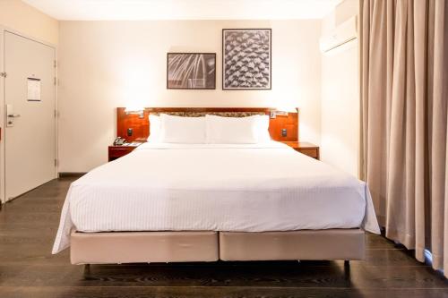 a bedroom with a large bed with white sheets at Double Tree by Hilton São Paulo Itaim in Sao Paulo