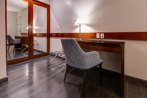 a room with a chair and a desk with a mirror at Double Tree by Hilton São Paulo Itaim in Sao Paulo