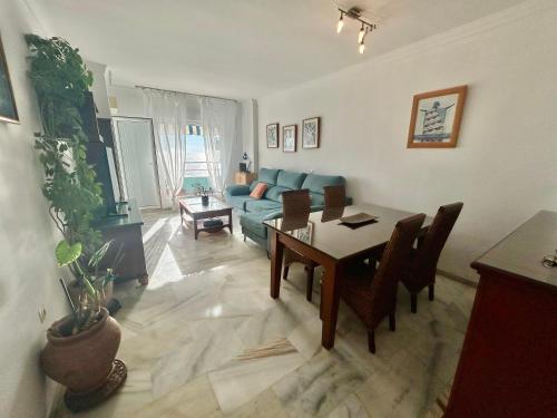un salon avec une table et un canapé bleu dans l'établissement GATU PREMIUM Villa Isabel TERRAZA,PARKING,1ºLINEA PLAYA,WIFI,VISTA AL MAR, à Cadix