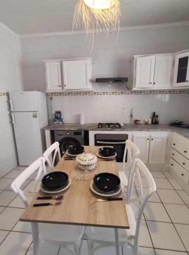 Una cocina con mesa de madera y electrodomésticos blancos. en N17 Bis, en Dar el Ouzir