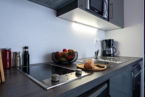 a kitchen with a counter top with a bowl of fruit at Nemea Appart Hotel Quai Victor Tours Centre in Tours