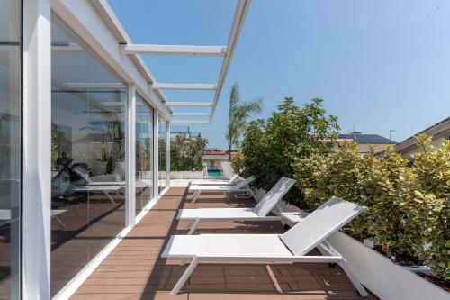 - une rangée de chaises longues blanches sur le balcon d'un bâtiment dans l'établissement Hotiday Apartments Giulianova, à Giulianova