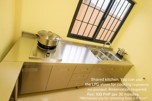 a kitchen with a sink and a pot on a stove at T1 Stay Manila-Near NAIA Manila Airport and PITX in Manila