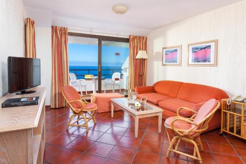 a living room with a couch and a table with chairs at Apartamentos Masaru in Puerto de la Cruz