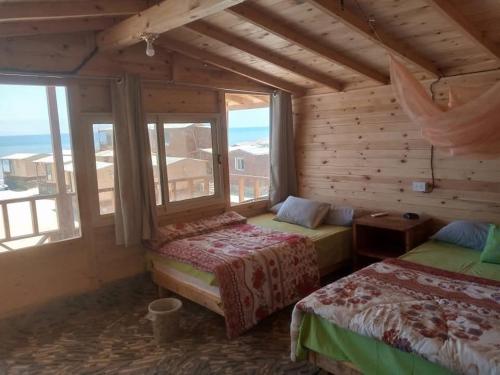 a bedroom with two beds and a large window at The Uniqueness Camp in Nuweiba‘ el Muzeinah