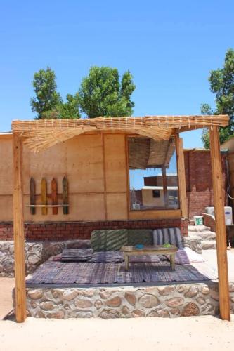 a wooden house with a bench and a table at The Uniqueness Camp in Nuweiba‘ el Muzeinah
