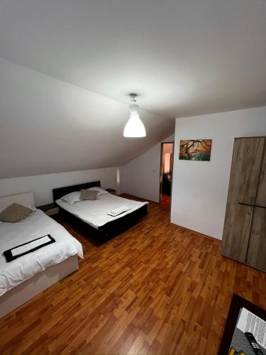 two beds in a room with wooden floors at Casa NIB Calimanesti in Călimăneşti