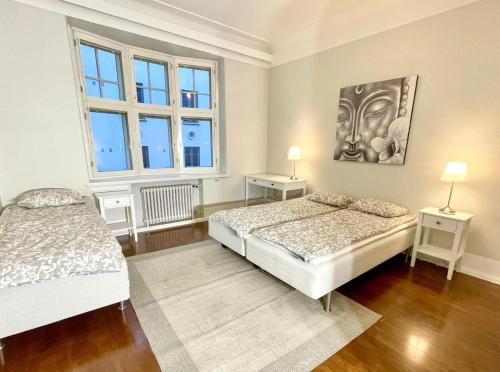 a bedroom with two beds and two windows at Elegant Jugend city retreat 79m2 in Helsinki