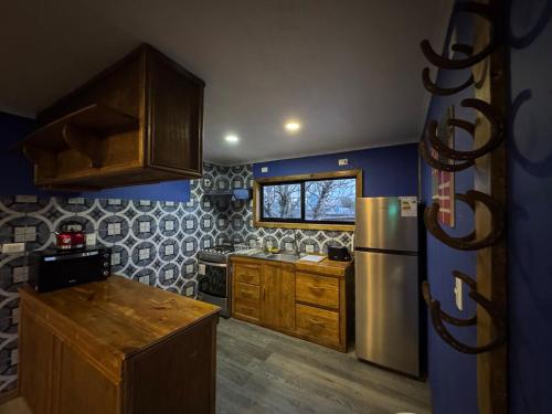 eine Küche mit Edelstahlkühlschrank und Holzschränken in der Unterkunft Aur House in Puerto Natales