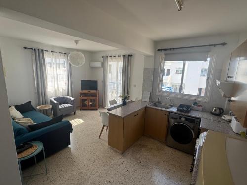 a kitchen and living room with a blue couch at Riana Latchi Apartment in Polis Chrysochous