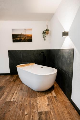 a bathroom with a white bath tub on a wooden floor at Hotel Gasthof Koch in Daaden
