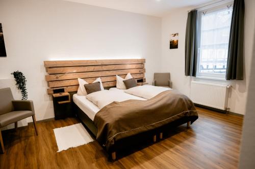 a bedroom with a large bed with a wooden headboard at Hotel Gasthof Koch in Daaden