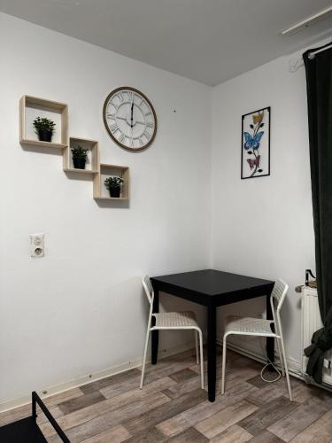 a table with two chairs and a clock on a wall at Deluxe Apartements Bobenheim Roxheim in Bobenheim-Roxheim