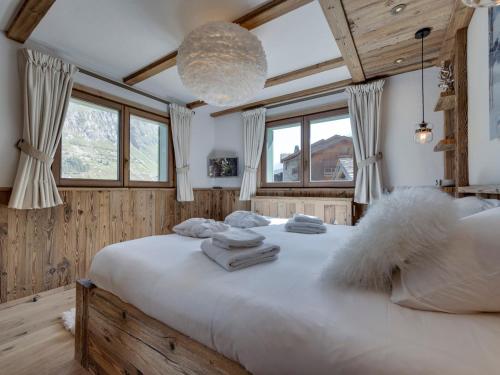 1 dormitorio con 1 cama grande con sábanas blancas y ventanas en Chalet skis aux pieds avec piscine et sauna à Val-d'Isère - FR-1-567-126, en Val dʼIsère