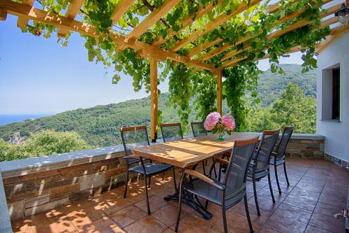 Una mesa y sillas de madera en un patio con vista. en Mila House, en Mouresi