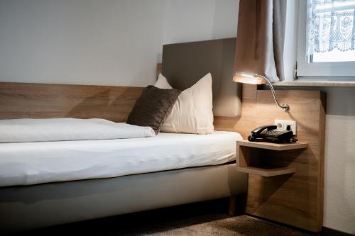 a bedroom with a bed and a lamp and a window at Hotel Gasthof Koch in Daaden