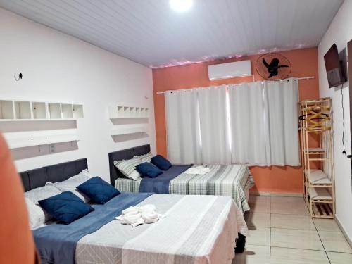 two beds in a room with orange walls at Hospedagem Aconchego Do Lar in Barreirinhas