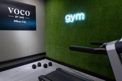 a room with a gym with a green wall at voco Bilbao - City by IHG in Bilbao