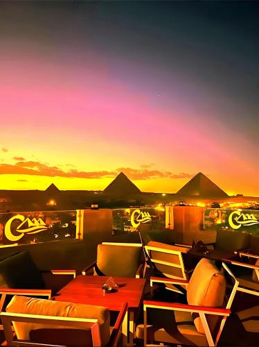 a table and chairs on a balcony with a sunset at Pyramids Nomad View Hotel in Cairo
