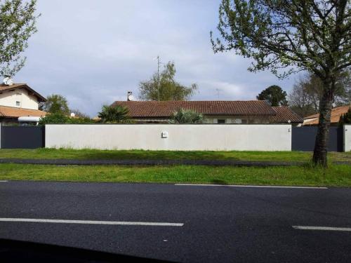 a street with a white wall and a tree at Maison paisible in Gujan-Mestras