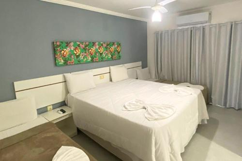 a bedroom with two beds and a painting on the wall at RESIDENCIAL MAR GALILÉIA in Porto Seguro