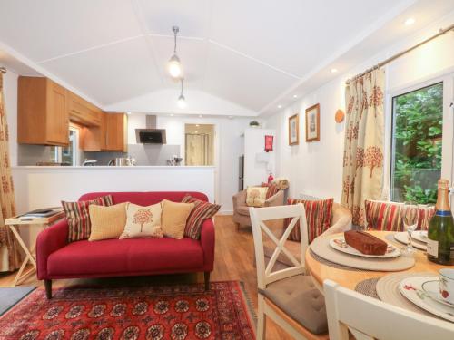 a living room with a red couch and a table at Orchard Lodge in Haywards Heath