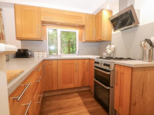 a kitchen with wooden cabinets and a stove top oven at Orchard Lodge in Haywards Heath