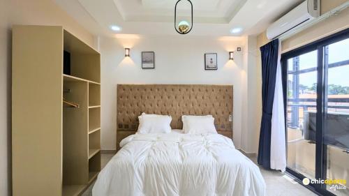 a bedroom with a bed with white sheets and a window at Chic & spacious studio with parking in Yaoundé