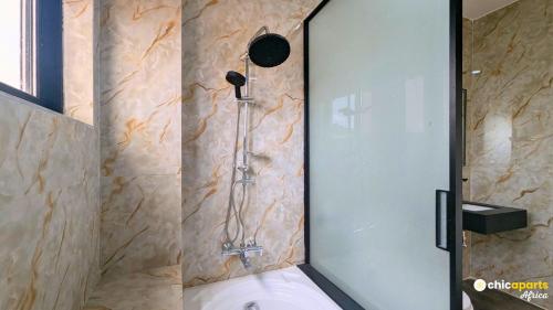 a shower with a glass door in a bathroom at Chic & spacious studio with parking in Yaoundé