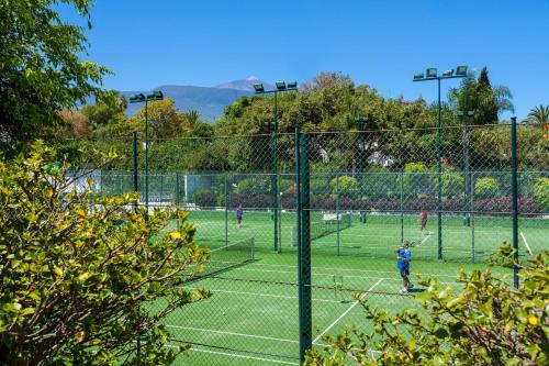 a group of people playing tennis on a tennis court at Apartamentos Masaru in Puerto de la Cruz