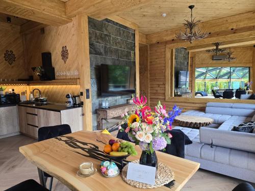 Sobiczkowy Dwór Apartament - Giewont Premium DeLuxe & SPA في كوشتيليسكا: غرفة معيشة مع طاولة عليها زهور