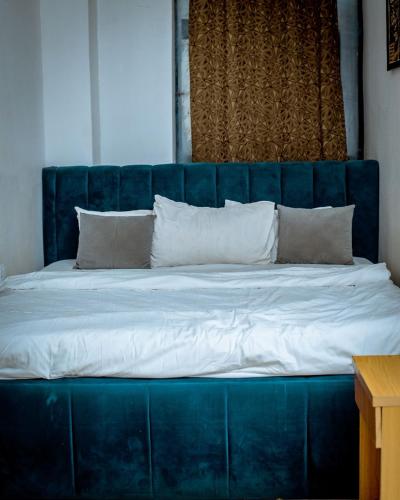 a large blue bed with white sheets and pillows at Padelia Hotels Ltd in Nsukka