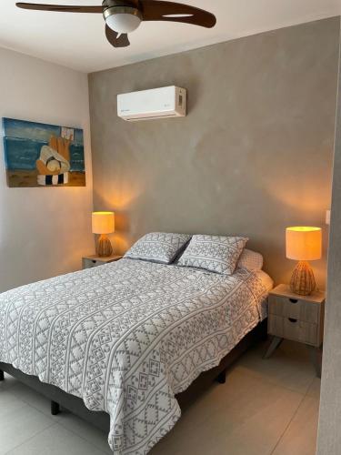 a bedroom with a bed with two lamps and a fan at Depto Moderno Oceanna frente a playa cerritos in Mazatlán