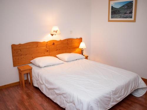 Un dormitorio con una gran cama blanca con dos almohadas. en 2 pièces 4 pers avec balcon et coin cuisine équipé - FR-1-504-537, en Superdevoluy