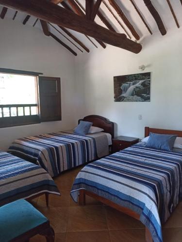 a bedroom with three beds and a window at cabañas villa Angelica in Barichara