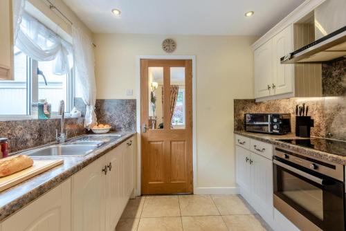 a kitchen with white cabinets and a sink and a door at 2 Bed in Pooley Bridge oc-c33318 in Pooley Bridge