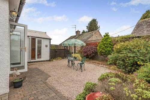 a garden with two chairs and an umbrella at 2 Bed in Pooley Bridge oc-c33318 in Pooley Bridge