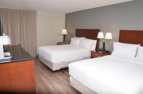 a hotel room with two beds and a desk with two lamps at Holiday Inn Bloomington Airport South-Mall Area by IHG in Bloomington