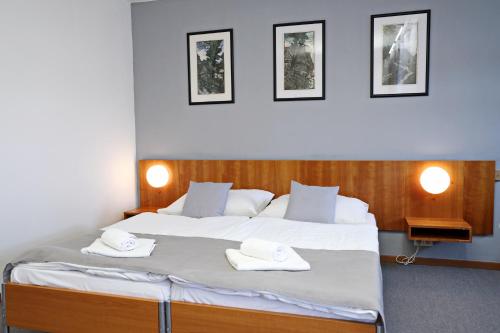 a bedroom with a large bed with two white towels at Hotel Maxim in Svätý Jur