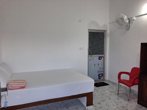 a bedroom with a white bed and a red chair at BEACH LIFE UPPUVELI in Trincomalee