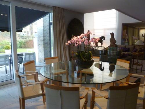 a dining room with a glass table and chairs at Villa Tiffany in Braine-lʼAlleud