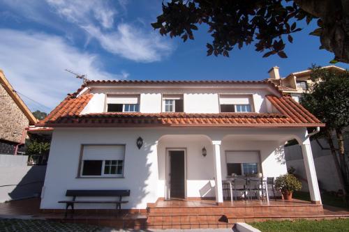 una casa blanca con un banco delante en Playa de Cesantes, en Pontevedra