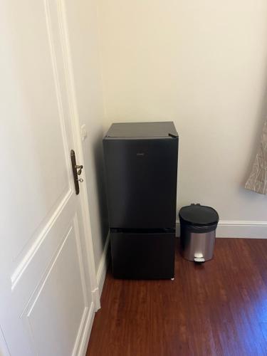 a small black refrigerator in a room next to a door at Le Pontet in Miramont-de-Guyenne