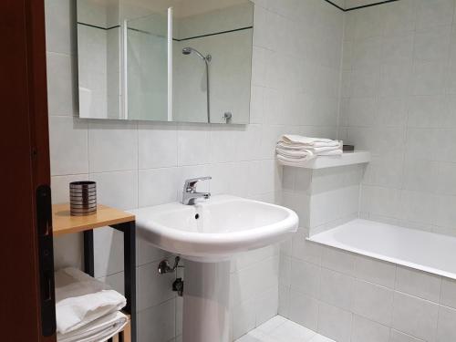 Baño blanco con lavabo y bañera en Appartamento Otelia, en Cremona