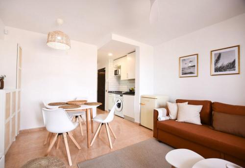 ein Wohnzimmer mit einer Couch und einem Tisch und Stühlen in der Unterkunft Oasis Duna Casa Maho in Corralejo