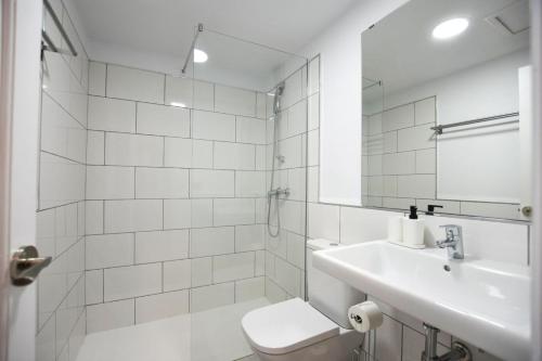 ein Badezimmer mit Waschbecken, Toilette und Spiegel in der Unterkunft Oasis Duna Casa Maho in Corralejo