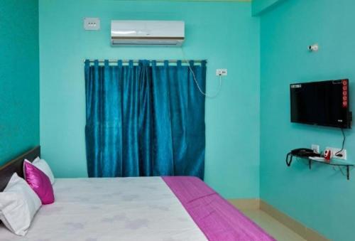 a bedroom with a bed with blue walls and a television at Deb Guest House 2 