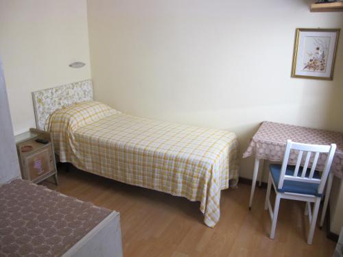 a room with two beds and a table and a chair at Hotel Conchiglia in Montecatini Terme