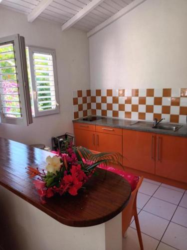 a kitchen with a wooden table with flowers on it at Residence Corail in Sainte-Rose